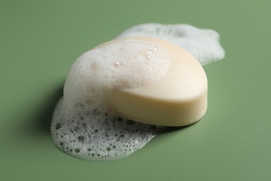 Soap and fluffy foam on green background
