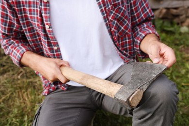 Man holding sharp ax with wooden handle outdoors, closeup