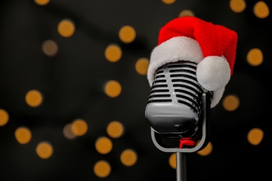 Retro microphone with Santa hat against blurred lights, space for text. Christmas music
