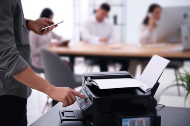 Employee using modern printer in office, closeup