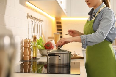 Woman with pot of fresh bouillon in kitchen. Homemade recipe