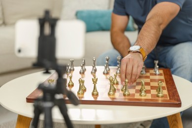 Photo of Teacher near chessboard conducting online lesson at home, closeup. Time for hobby
