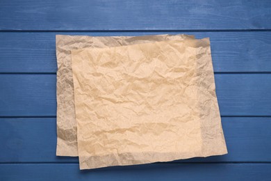Photo of Sheets of baking paper on blue wooden table, top view