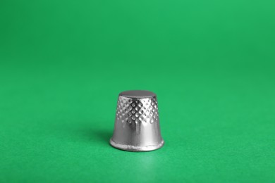 Photo of Silver thimble on green background. Sewing accessory