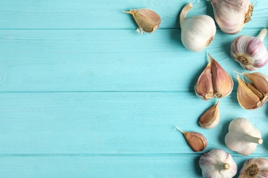 Fresh unpeeled garlic bulbs and cloves on light blue wooden table, flat lay with space for text. Organic product