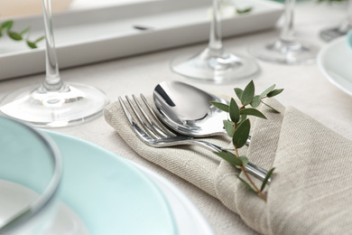 Elegant cutlery with green leaves on table, closeup. Festive setting