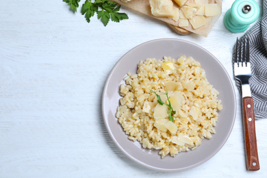 Delicious risotto with cheese on white wooden table, flat lay