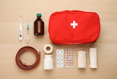 First aid kit on light wooden table, flat lay
