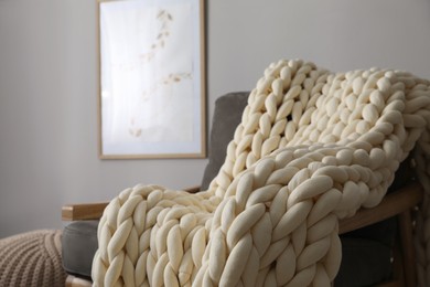 Soft chunky knit blanket on armchair in room