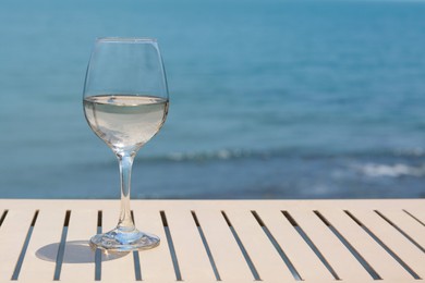 Glass with wine on table near sea. Space for text