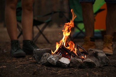 People near bonfire with burning firewood outdoors, closeup