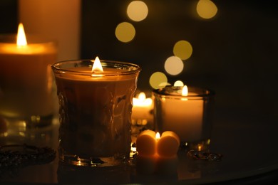 Photo of Beautiful burning candles on table in darkness. Space for text
