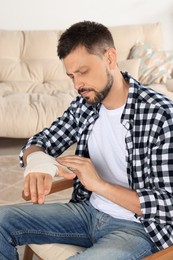 Man applying medical bandage onto hand at home