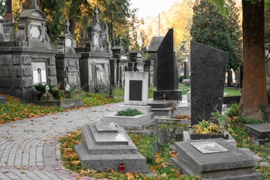 Many tombstones and paved footpath at cemetery