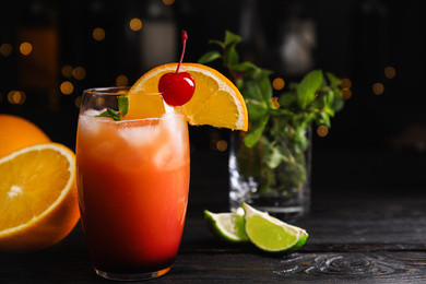 Fresh alcoholic Tequila Sunrise cocktail on black wooden table