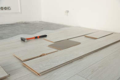 Parquet planks and hammer on floor in room prepared for renovation