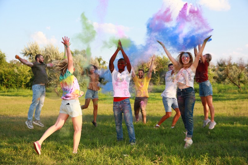 Photo of Happy friends having fun with colorful powder dyes outdoors. Holi festival celebration