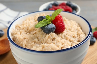 Tasty oatmeal porridge with berries in bowl, closeup