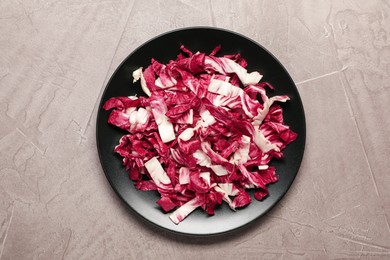 Cut radicchio in plate on grey table, top view