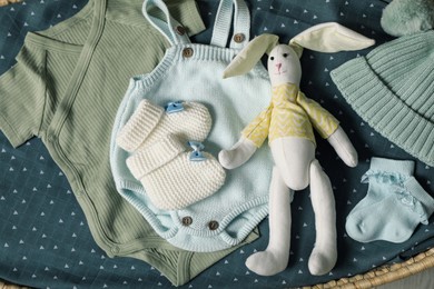 Baby clothes and accessories on blue fabric, flat lay