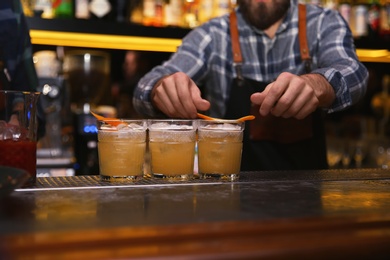 Bartender preparing tasty cocktail at table in nightclub, closeup