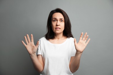 Mature woman feeling fear on grey background