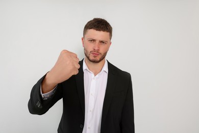 Aggressive young man showing fist on white background
