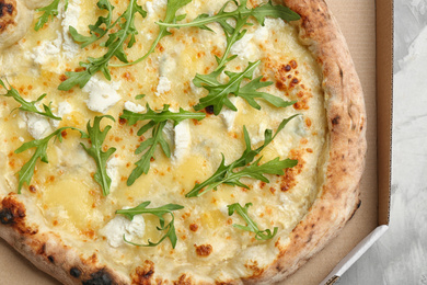 Delicious cheese pizza with arugula in takeout box, closeup