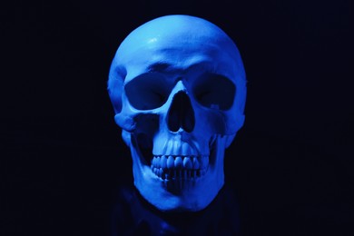 Blue human skull with teeth on black background