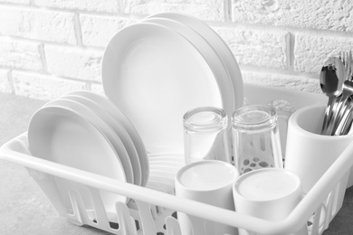 Dish drainer with clean plates on table, closeup