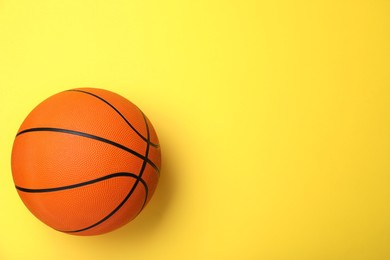Orange ball on yellow background, top view with space for text. Basketball equipment