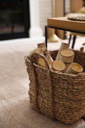 Firewood in wicker basket in room, closeup view