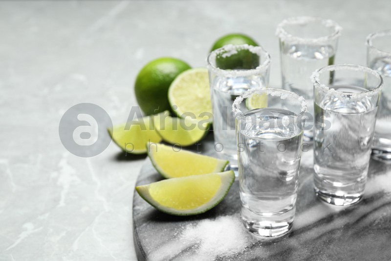 Mexican Tequila shots, lime slices and salt on grey marble table