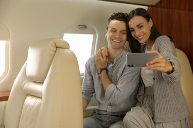 Lovely young couple taking selfie in airplane during flight