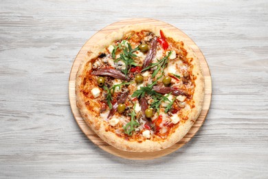 Photo of Tasty pizza with anchovies, arugula and olives on grey wooden table, top view