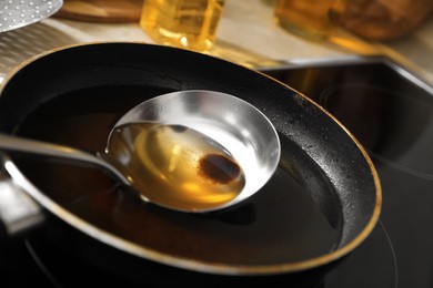 Frying pan and ladle with used cooking oil on stove, closeup