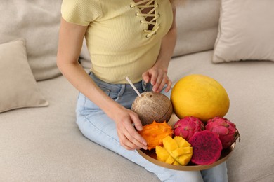 Photo of Young woman with fresh exotic fruits on sofa, closeup