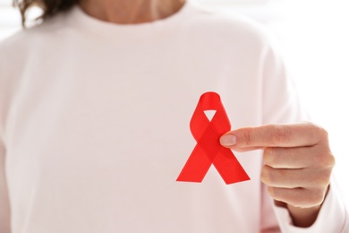 Woman holding red awareness ribbon, closeup with space for text. World AIDS disease day