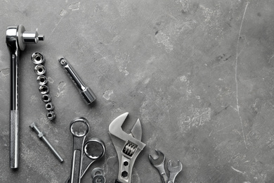 Photo of Auto mechanic's tools on grey stone table, flat lay. Space for text