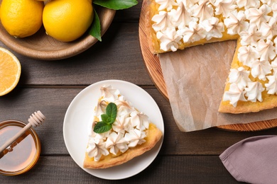 Cut delicious lemon meringue pie served on wooden table, flat lay