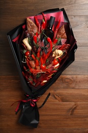 Beautiful edible bouquet with meat, cheese and vegetables on wooden table, top view