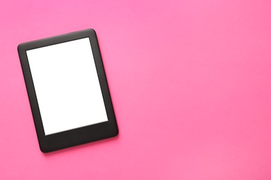 Modern e-book reader with blank screen on pink background, top view. Space for text