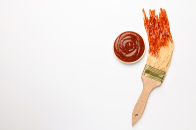 Photo of Brush painting with spaghetti dipped in ketchup on white background, top view. Space for text. Creative concept