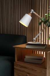 Photo of Stylish modern desk lamp and book on wooden cabinet in living room