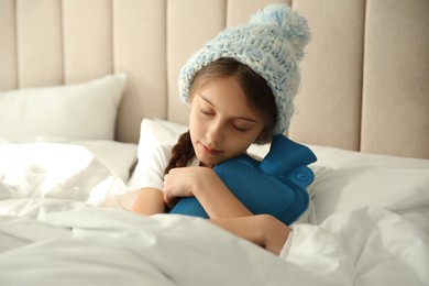 Ill girl with hot water bottle suffering from cold in bed at home