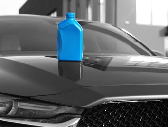 Photo of Blue canister with motor oil on hood of car outdoors