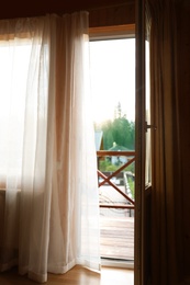 Open balcony door with curtain in apartment