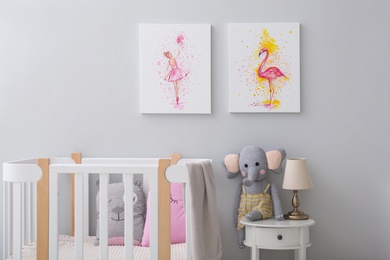 Children's room with comfortable crib and pictures on grey wall. Interior design