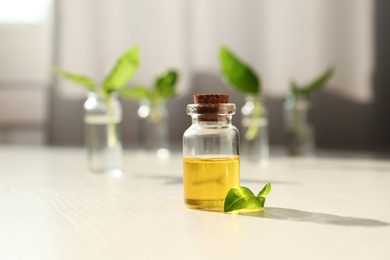 Bottle of essential basil oil on table against blurred background