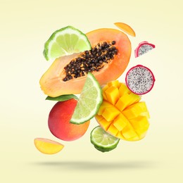 Image of Many fresh tropical fruits falling on light pale yellow background
